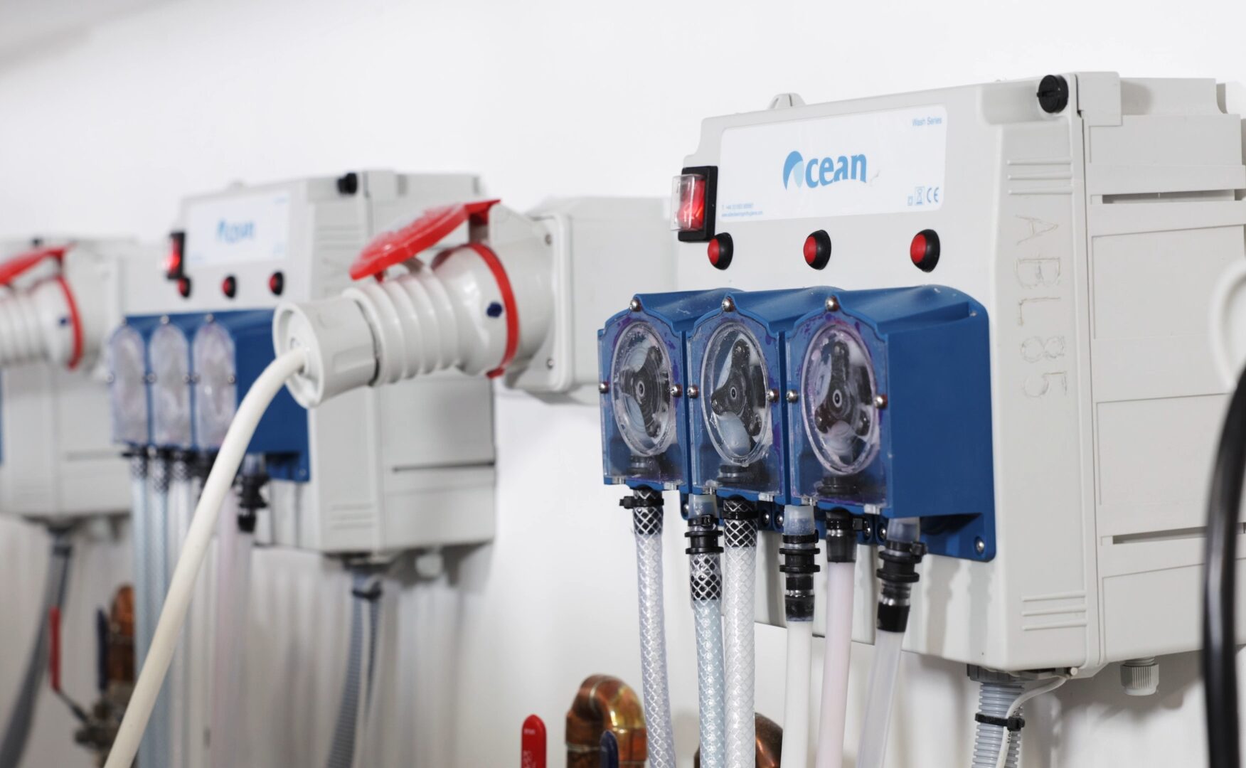 An auto dose system on the wall. A great Eco-Friendly Laundry Solutions for Care Homes. It's blue and grey with dials for dispensing laundry chemicals.