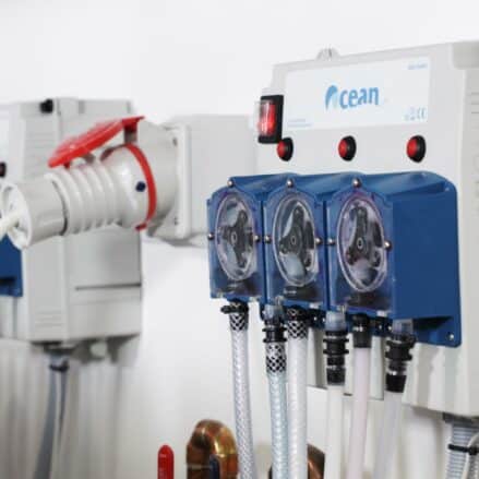 Close-up of industrial equipment featuring power cables, a control panel, and three connected hoses. about