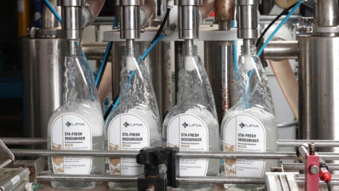 Bottling process of Sta-Fresh Deodoriser shown in a factory setting, with four bottles being filled by a machine.
