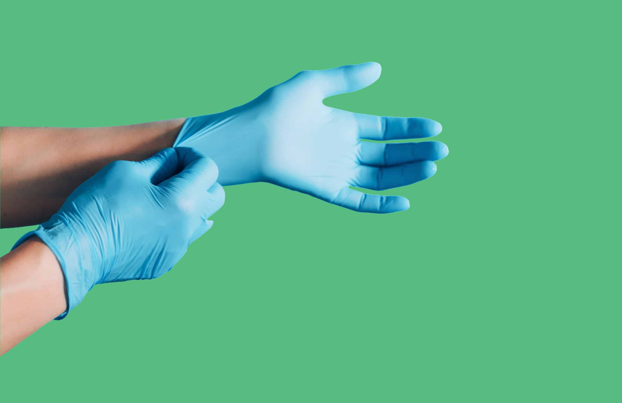 Blue Nitrile gloves being applied against a green background