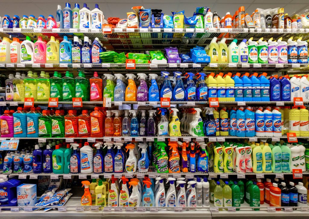 Supermarket shelf stocked with a variety of general purpose and multipurpose cleaning spray bottles