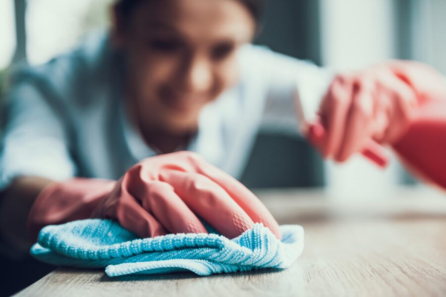 Care home staff member wearing gloves cleaning a table with a cloth