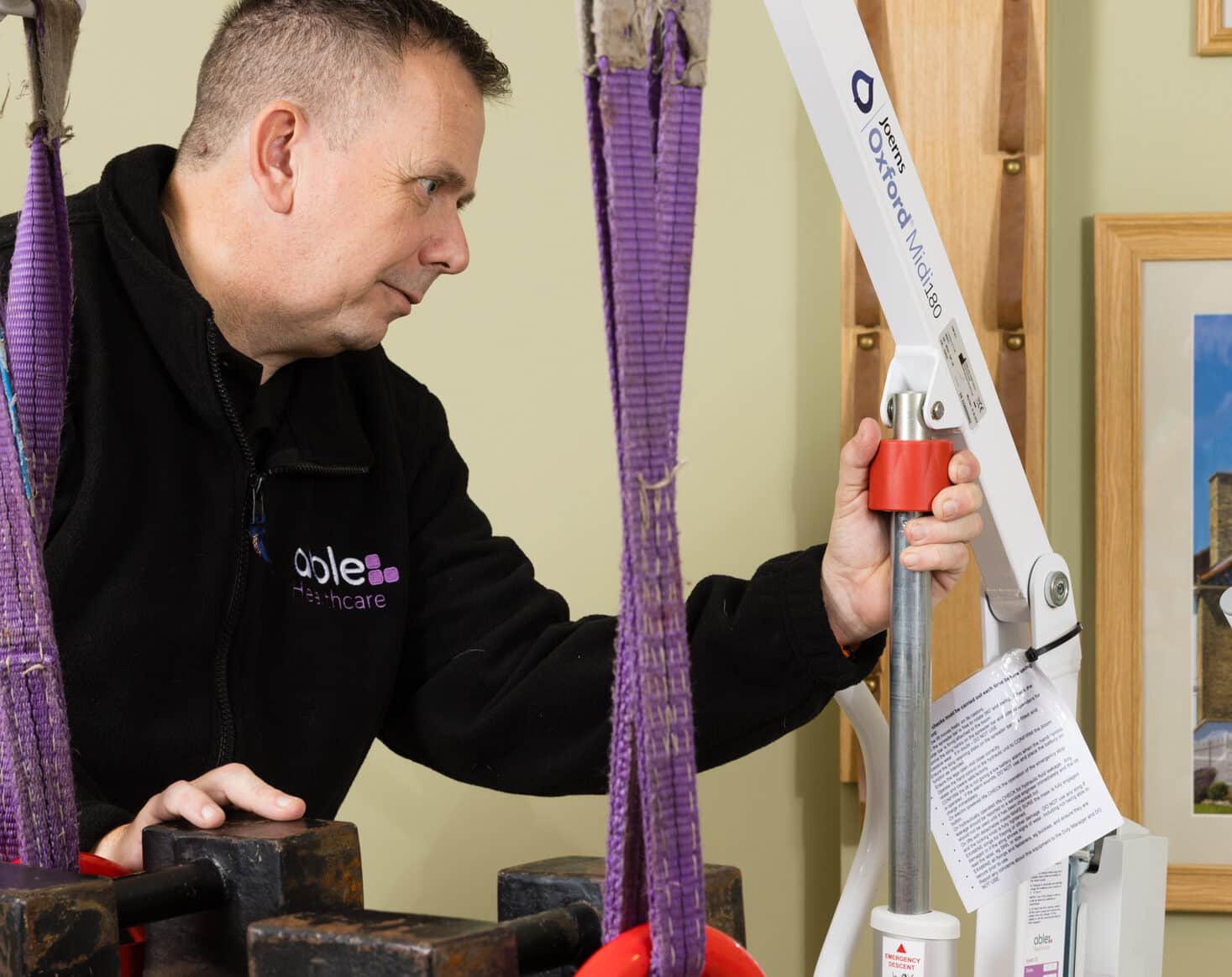 Technician performing safe working load test on hoist during LOLER inspection in care home