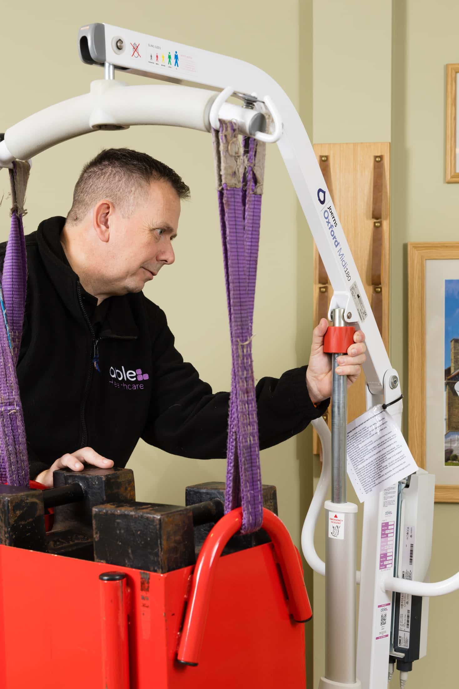 Technician performing safe working load test on hoist during LOLER inspection in care home