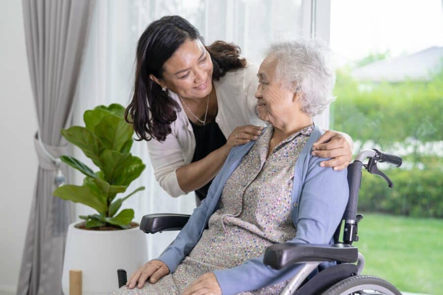 Caregiver supporting elderly woman in a crash tested wheelchair at a care home