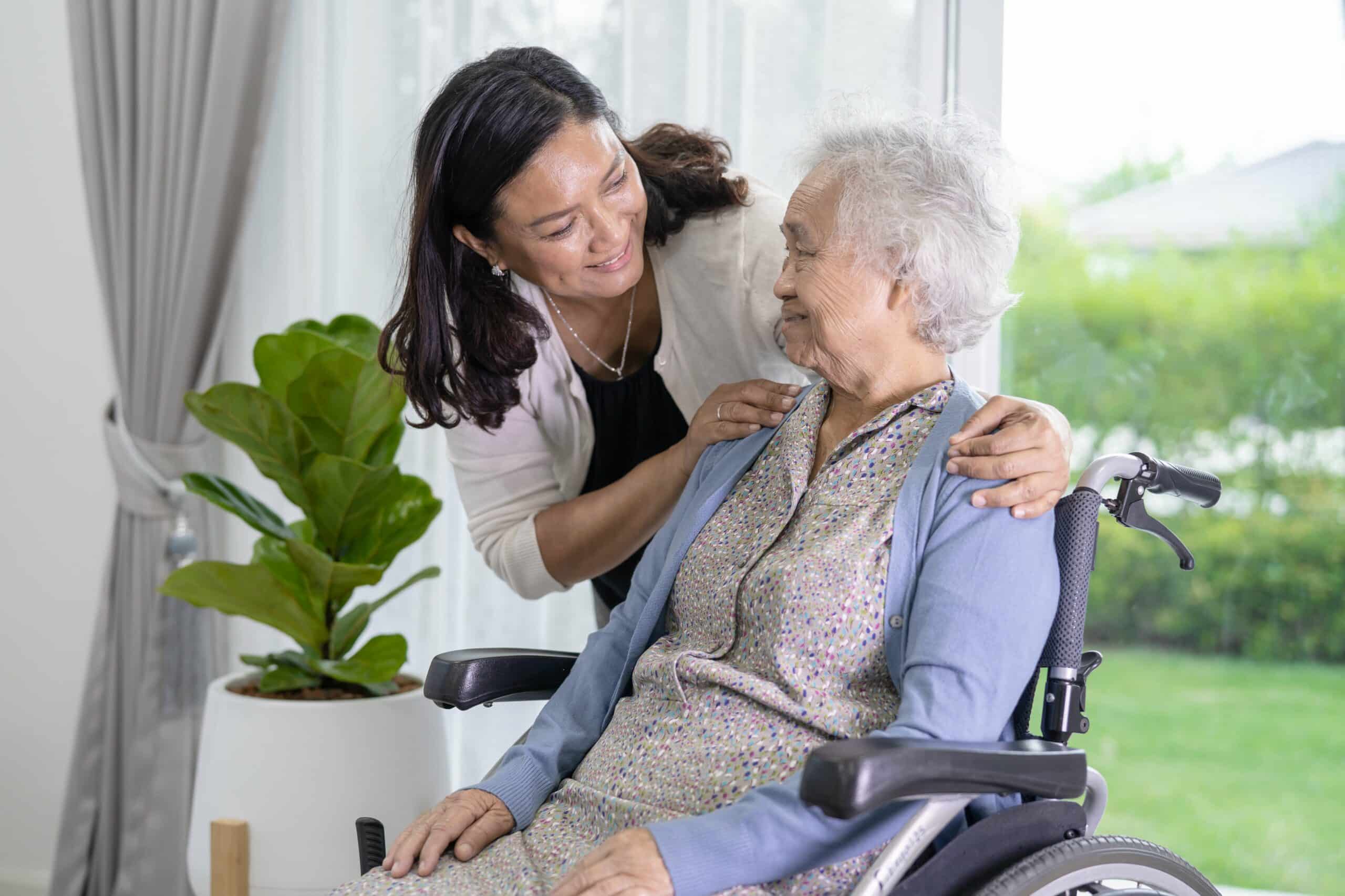 Caregiver supporting elderly woman in a crash tested wheelchair at a care home