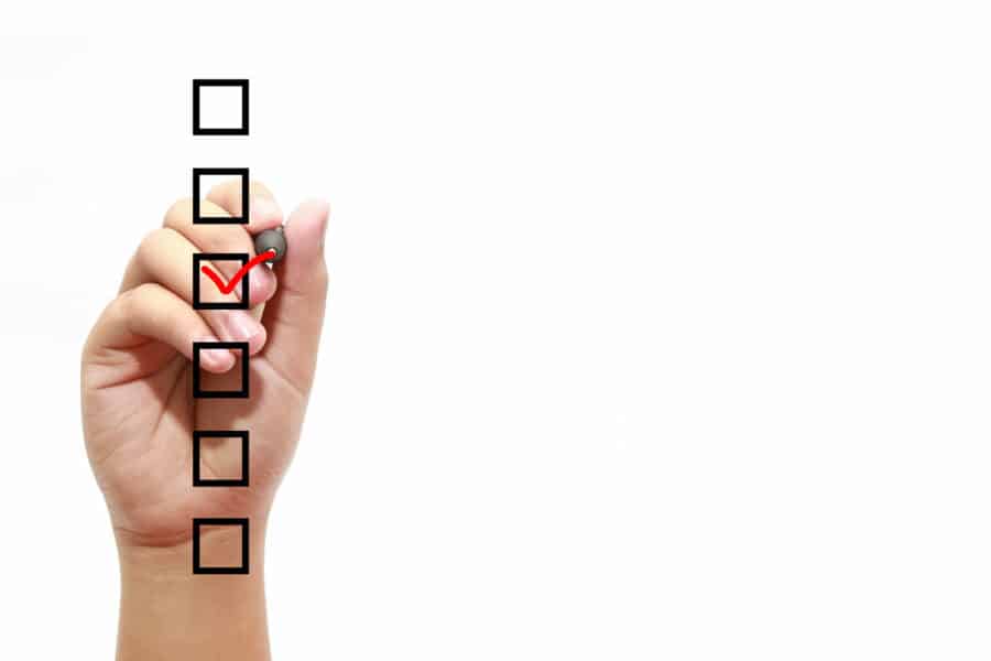 Hand ticking a checkbox on a LOLER inspection checklist for care homes