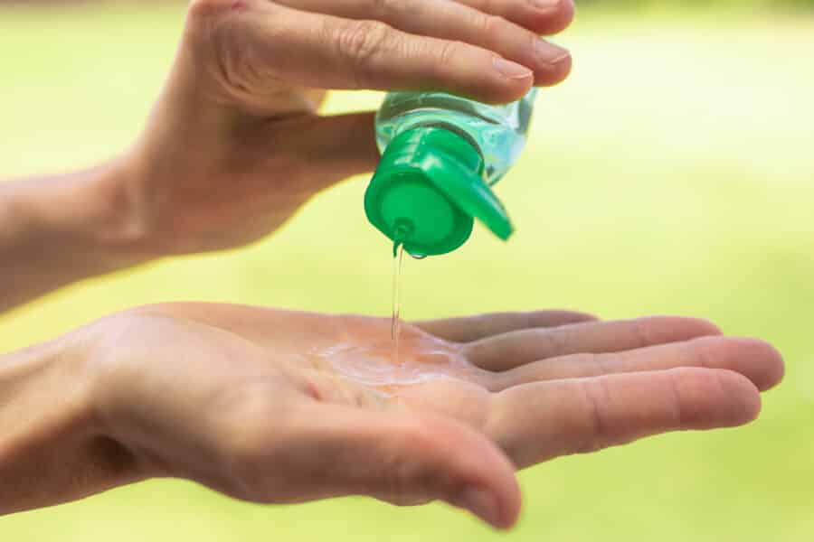 Person applying sanitiser gel to hands, illustrating sanitiser gel vs sanitiser foam in care homes.