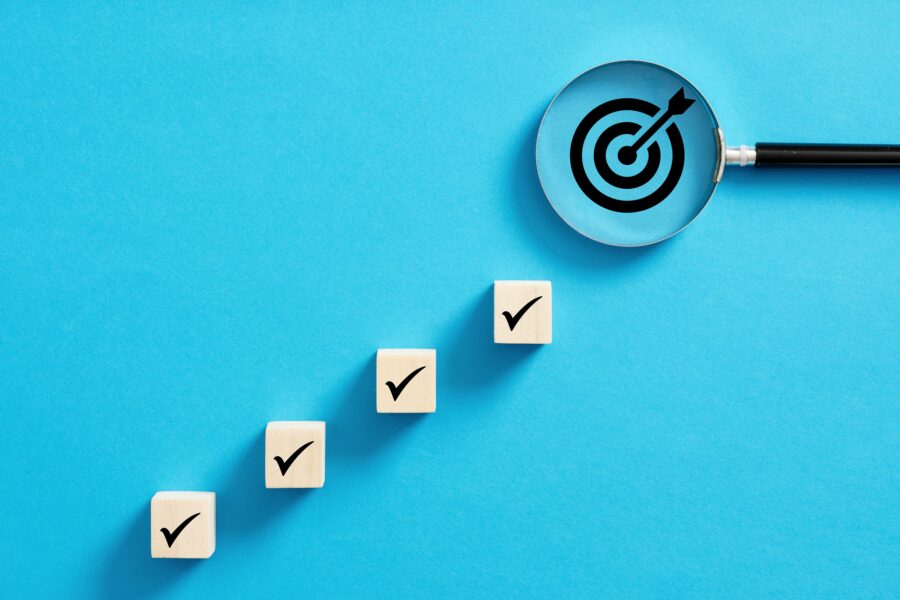 Checklist steps leading to a target under a magnifying glass, symbolising the CQC single assessment framework