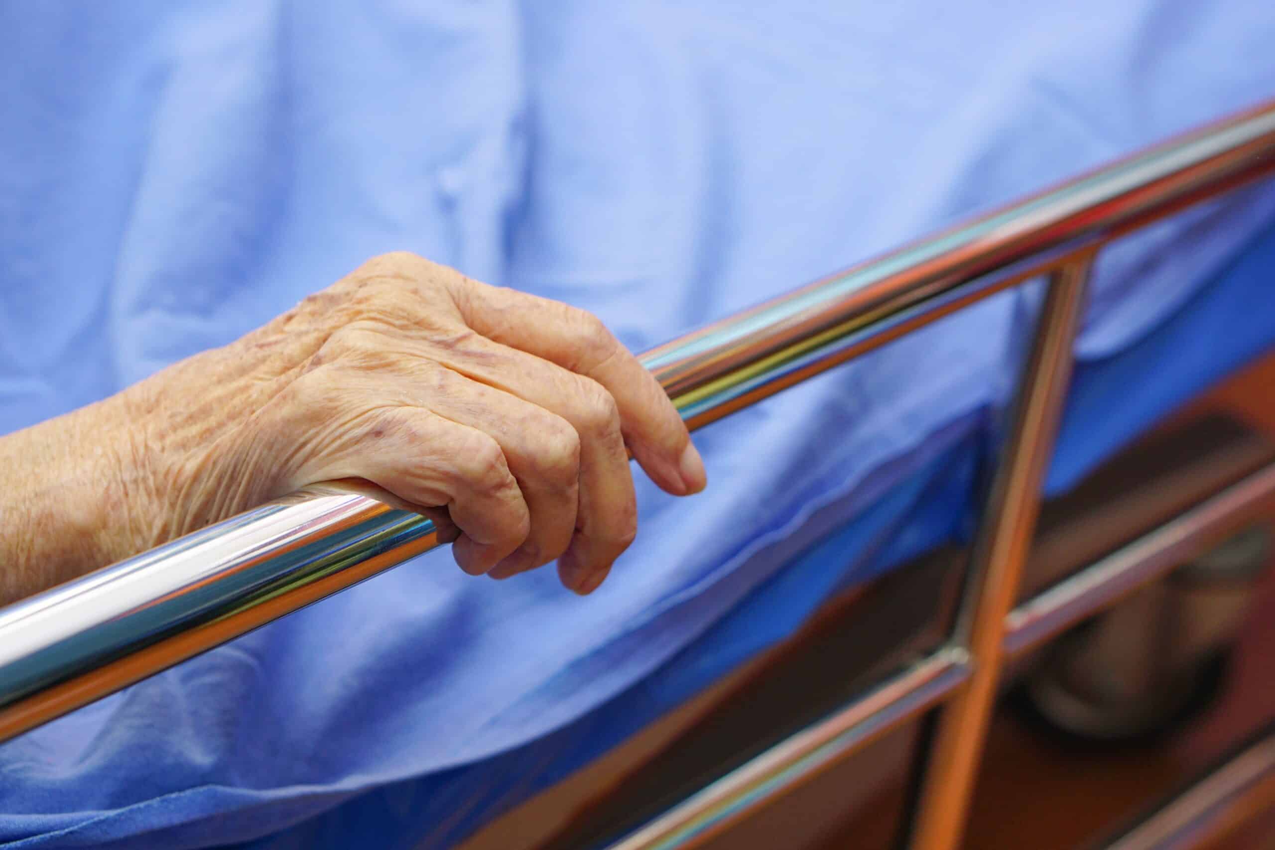 Resident hand holding a bed rail; maintenance processes uphold Bed Rail Compliance in care homes